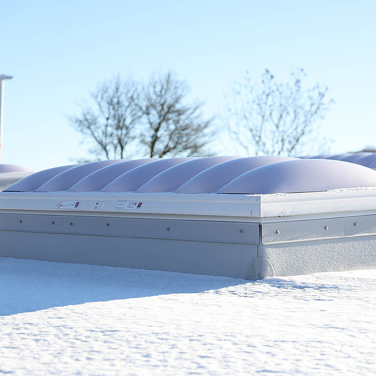 LAMILUX Lichtkuppel F100 W auf Flachdach bei winterlichen Bedingungen mit natürlichem Tageslichteinfall
