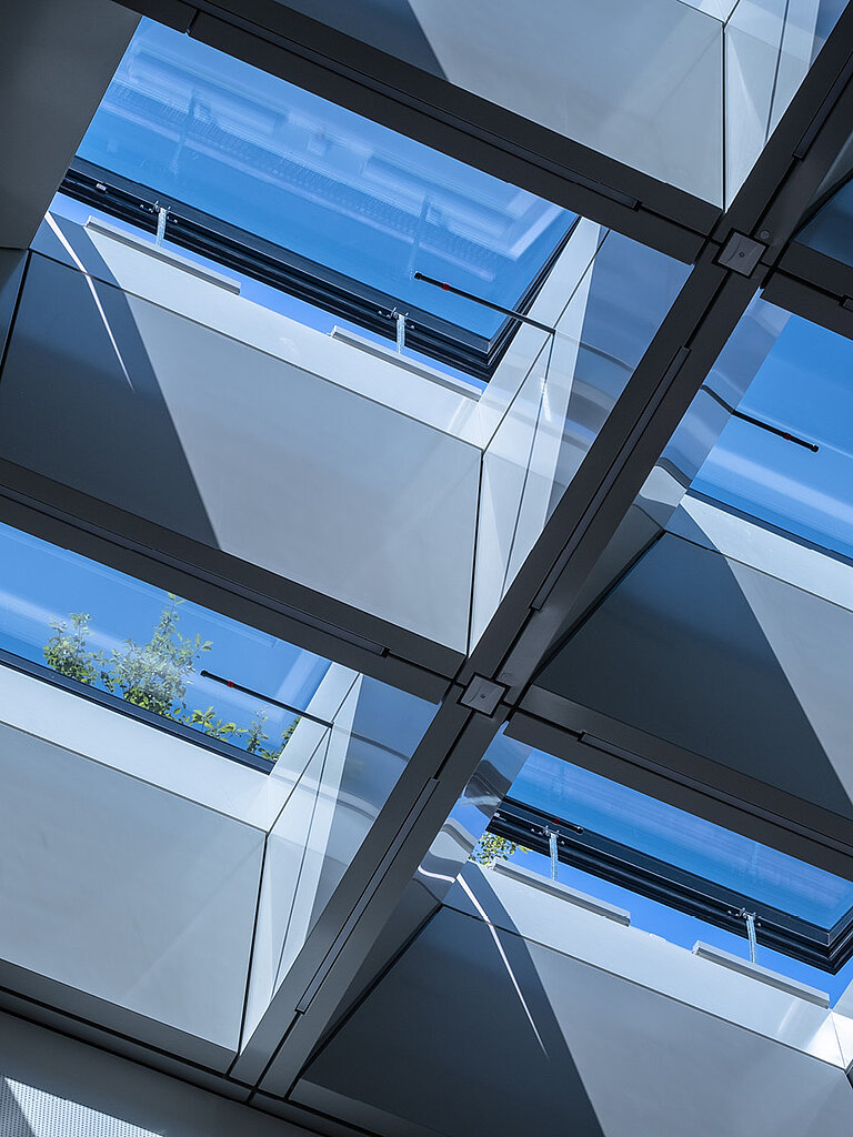 Innenansicht mehrerer geöffneter LAMILUX Flachdach Fenster FE RWA mit sichtbarer Tragkonstruktion und Blick in den Himmel