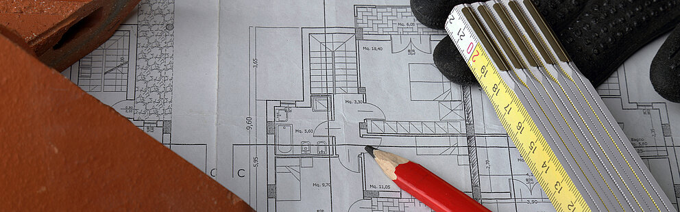 Architektur Grundriss mit rotem Bleistift, gelbem Zollstock und Arbeitshandschuhen auf technischer Zeichnung
