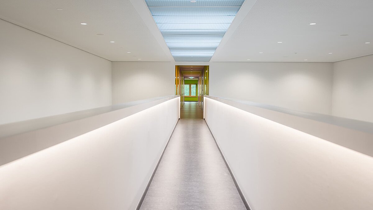 Modern gestalteter Flur im Markgraf-Georg-Friedrich-Gymnasium in Kulmbach mit Flachdach-Fenstern und indirekter Beleuchtung.