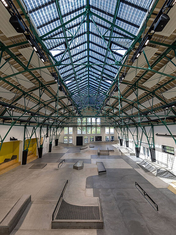 Skatehalle mit LAMILUX Glasdach PR60 und grünem Stahltragwerk in historischer Industriehalle.