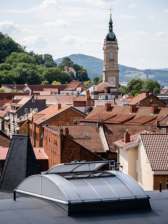 Dach der Kletterhalle "Alte Brauerei" in Eisenach mit LAMILUX Lichtbändern B, im Hintergrund historische Gebäude und Kirchturm.