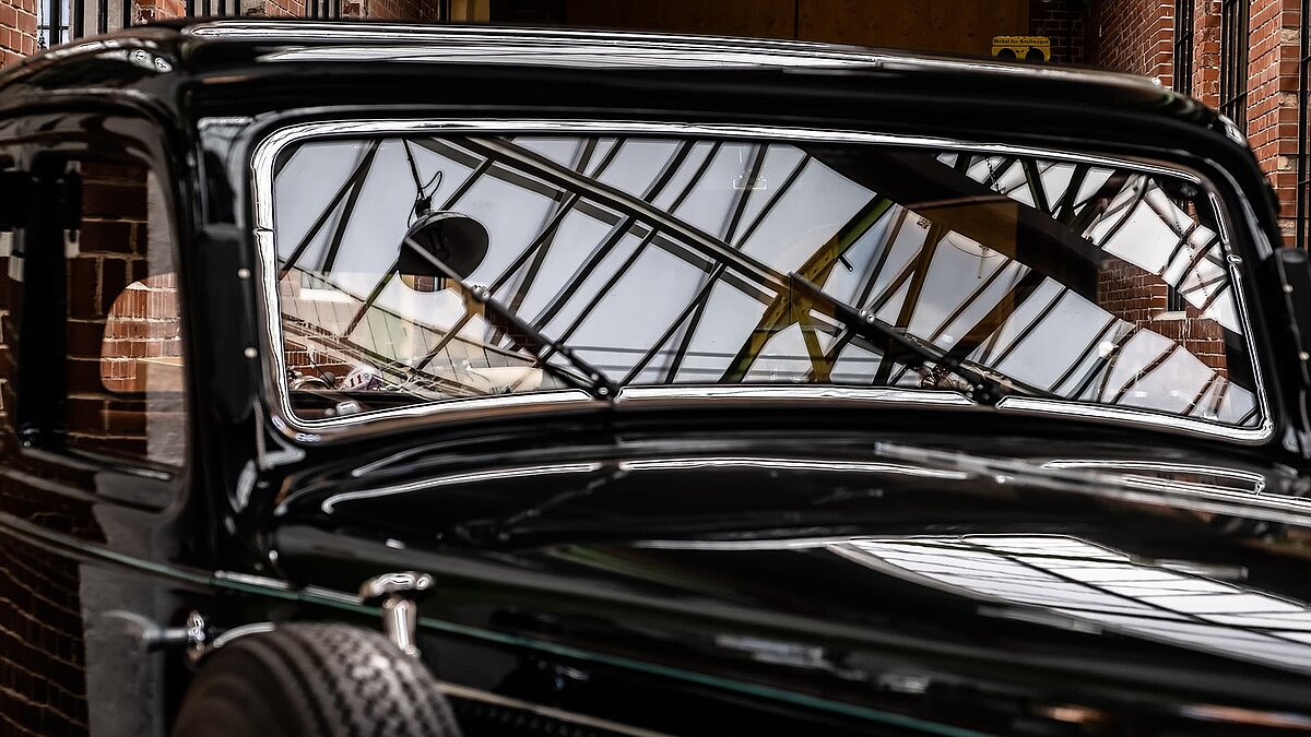 Nahaufnahme eines klassischen Oldtimers in der Eventhalle Zündmagnet in Wurzen mit dem Glasdach und industriellem Ambiente in der Windschutzscheibe.