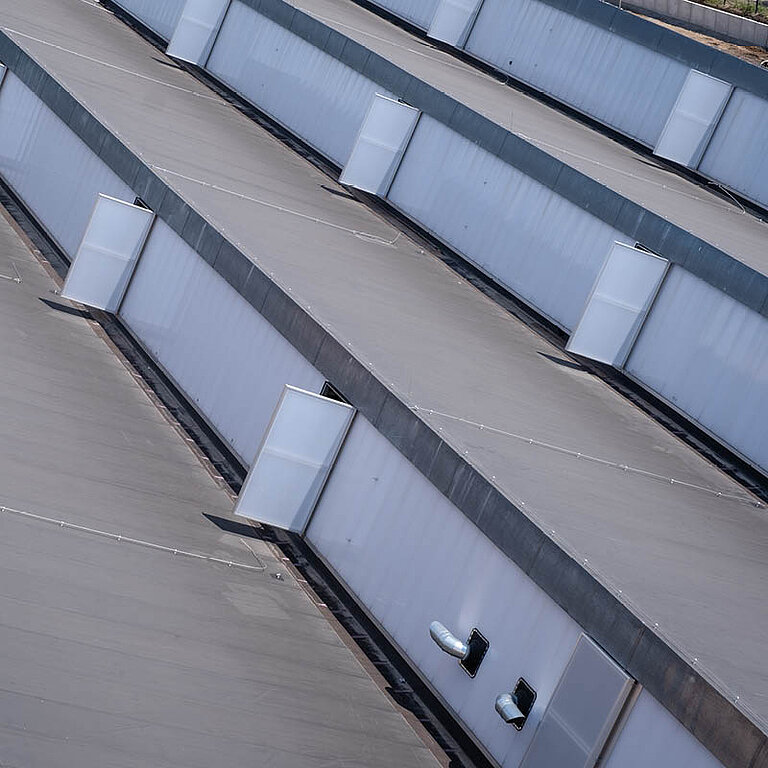 Mehrere geschlossene LAMILUX Lichtband W|R RWA entlang der Dachkante mit transluzenter Verglasung in Reihenanordnung