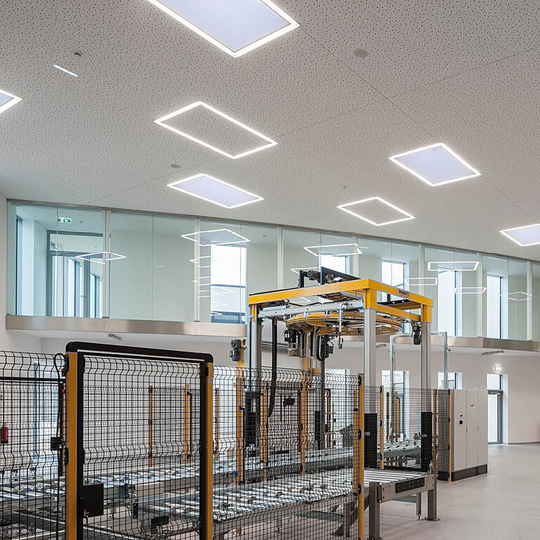Innenansicht einer Produktionshalle mit mehreren LAMILUX Flachdach Fenster F100 RWA in der Decke
