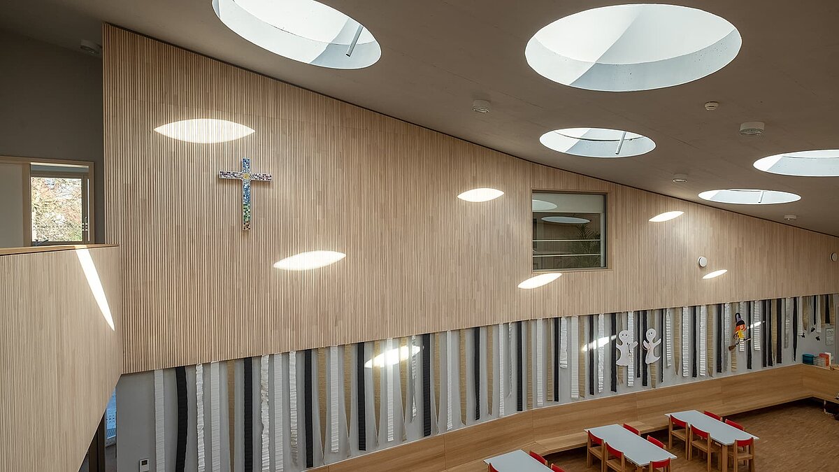 Innenansicht des Kindergartens St. Severin mit runden Flachdach-Fenstern, die natürliches Tageslicht hereinlassen.