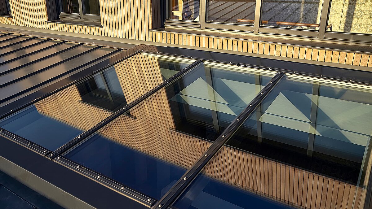 Detailansicht des LAMILUX Glasdachs PR60 bei den Potton Show Homes in England, mit Reflexion der Holzfassade und Fenstern.