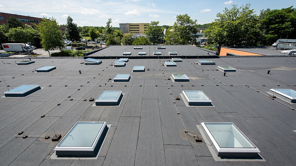 Flachdach der Caritas Hagen mit mehreren rechteckigen Dachfenstern und umliegender grüner Landschaft.