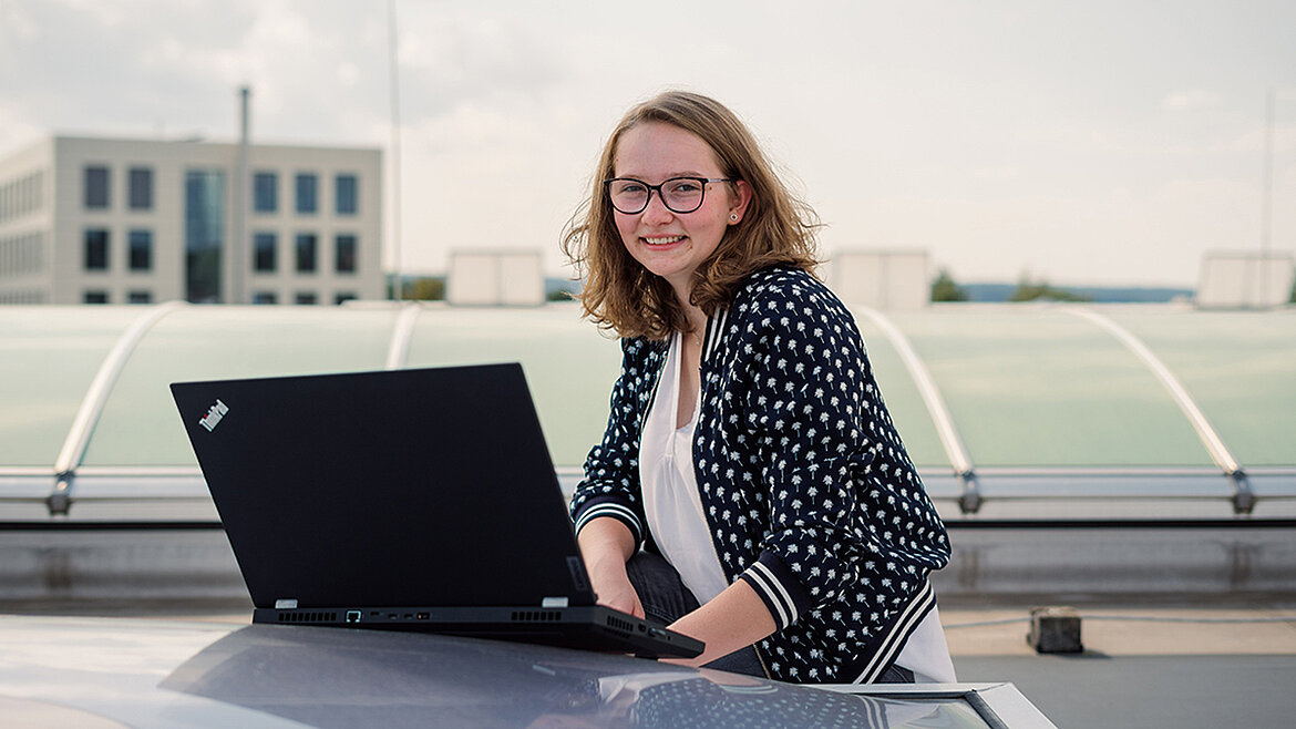 Frau arbeitet mit Laptop im Außenbereich auf dem Dach