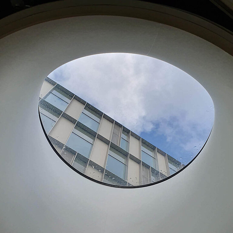 AMILUX Flachdach Fenster F100 rund mit weißem Innenrahmen, Blick nach außen durch runde Tageslichtöffnung