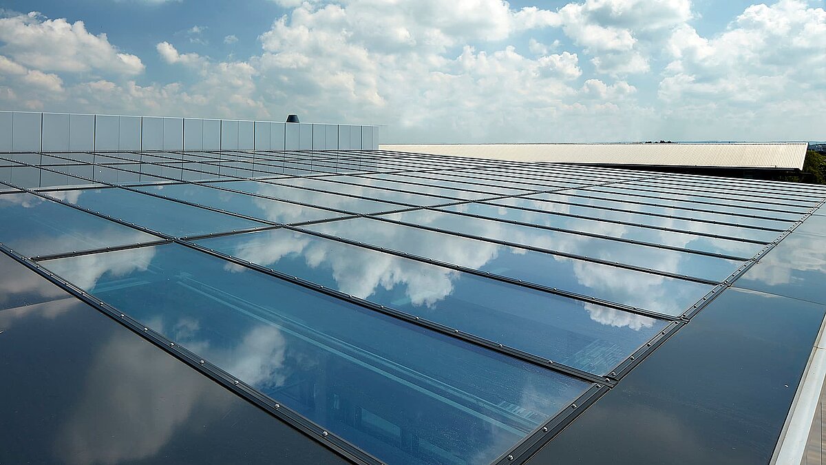 Glasdach der Gewerbeimmobilie im Milton Park, England, mit reflektierendem Himmel und Wolken auf der Oberfläche.