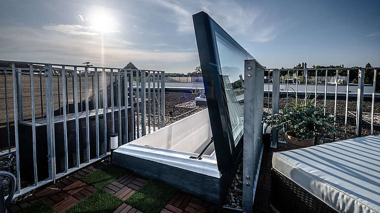 Geöffneter LAMILUX Flachdach Ausstieg auf begrüntem Dach mit sicherem Zugang und Geländer