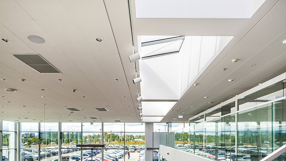 Blick von innen auf ein Glasdach über einem Autohaus mit Glaswänden