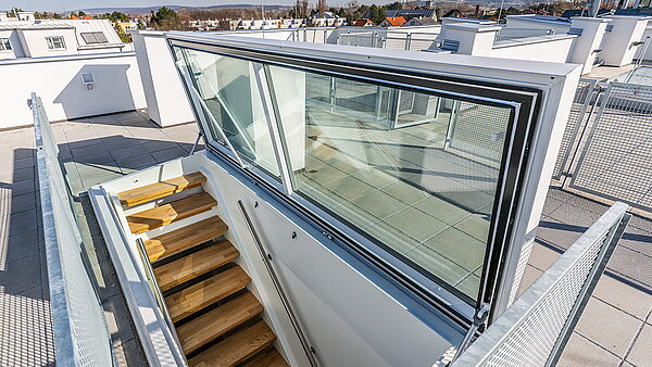 Flachdach Ausstieg von LAMILUX bei einem Wohnhaus in Korneuburg, moderne Treppe und Verglasung mit Ausblick auf die Umgebung.