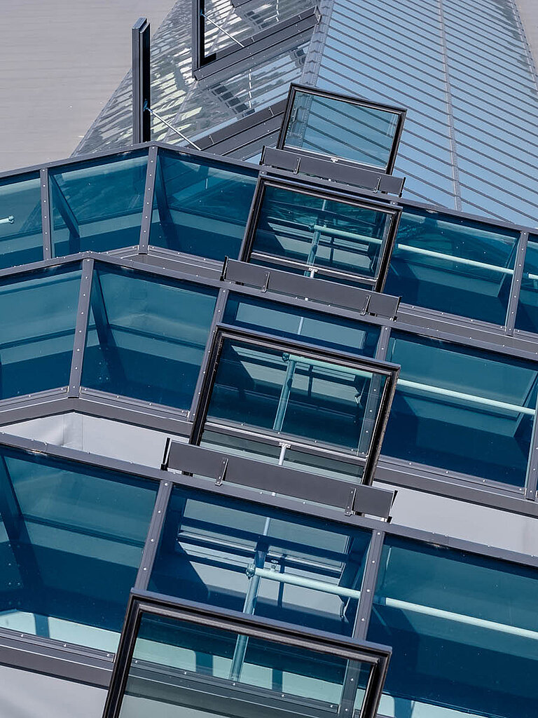 Mehrere geöffnete LAMILUX Glasdach RWA mit geneigter Verglasung und Metallrahmen auf Gebäudedach