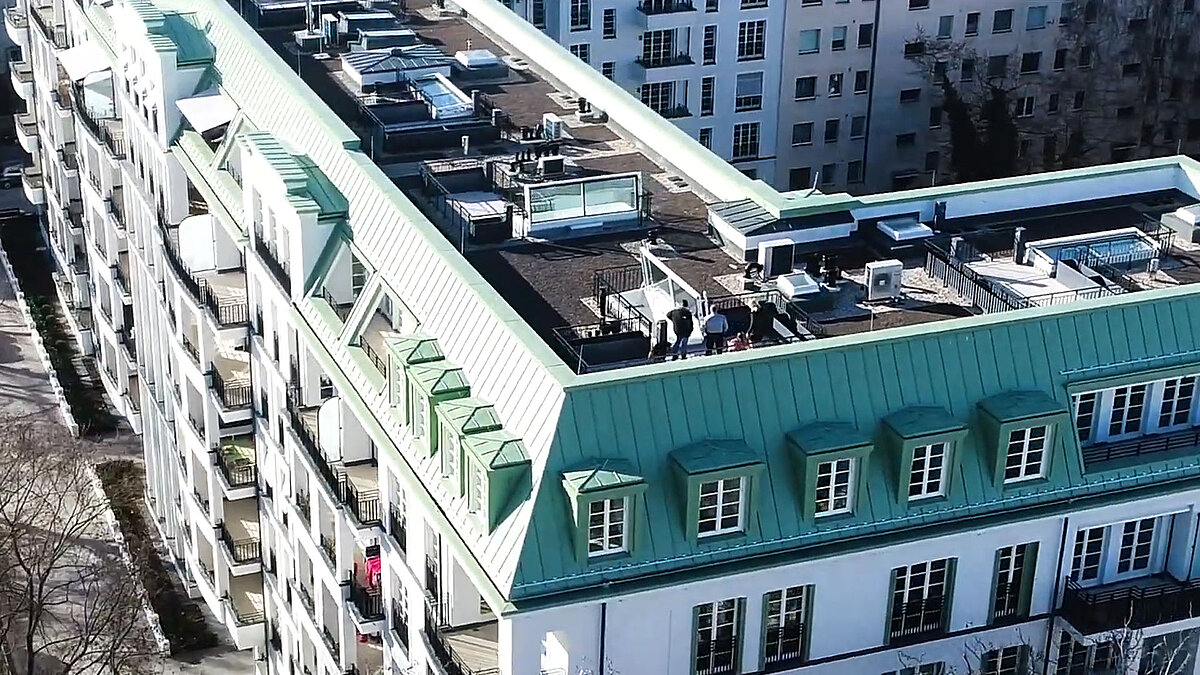 Drohnenaufnahme eines Wohngebäudes am Hochmeisterplatz in Berlin mit mehreren LAMILUX Flachdach Ausstiegen und begrüntem Dachbereich.