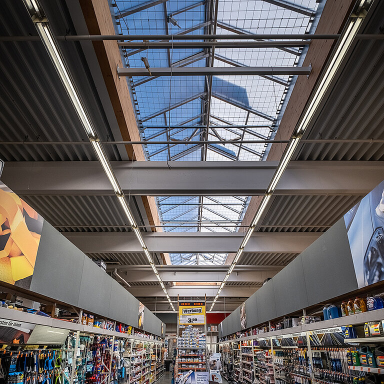Innenansicht eines LAMILUX Lichtband Satteldachform über moderner Verkaufsfläche mit intensivem Tageslichteinfall