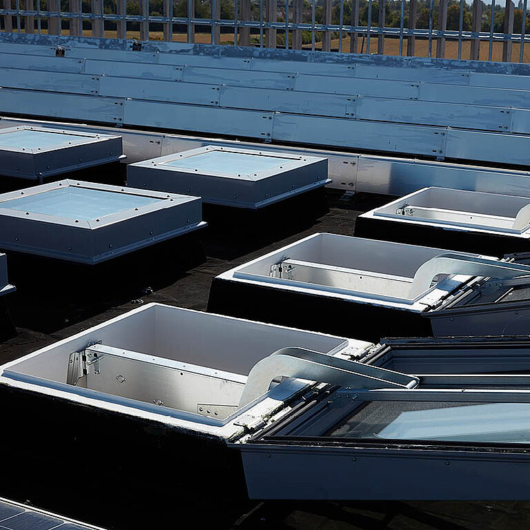 Mehrere geöffnete LAMILUX Flachdach Fenster FE RWA auf Industrie-Flachdach in Reihenanordnung