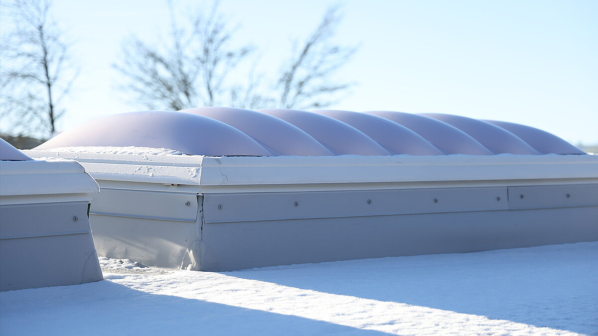 Eine Lichtkuppel F100W auf dem Dach des Gebäudes "Ab in die Box" am Diemelsee, die von Schnee bedeckt ist.