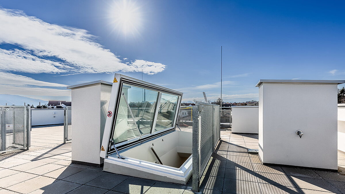 Flachdach Ausstieg von LAMILUX bei einem Wohnhaus in Korneuburg unter klarem Himmel und Sonnenschein.