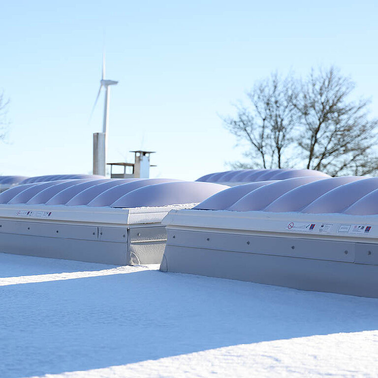 Mehrere LAMILUX Lichtkuppeln F100 W auf Flachdach bei winterlichen Bedingungen mit Schneebedeckung