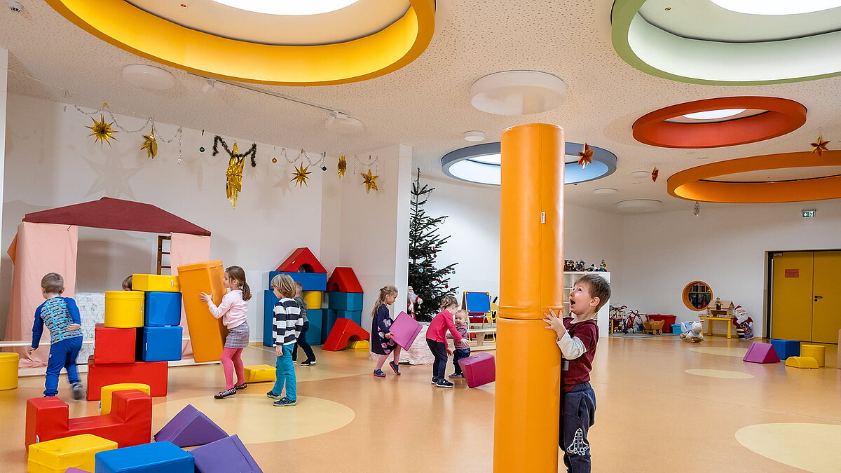 Spielende Kinder mit bunten Bausteinen in der Kindertagesstätte Glückliche Zukunft in Sömmerda, unter farbigen runden Oberlichtern.