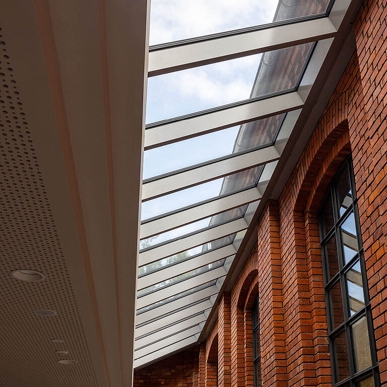 Glasdach Fire Resistance zwischen moderner Innenwand und historischer Ziegelfassade.
