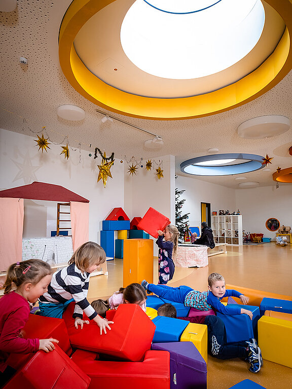 Kinder spielen in der Kindertagesstätte Glückliche Zukunft in Sömmerda unter einem bunten runden Flachdach Fenster 