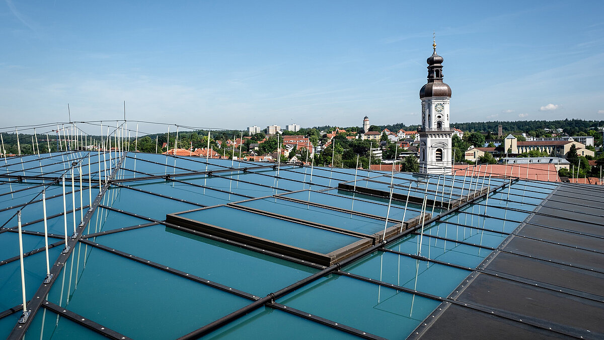 Blick auf das Glasdach des Diözesan Museums in Freising mit Kirchturm im Hintergrund