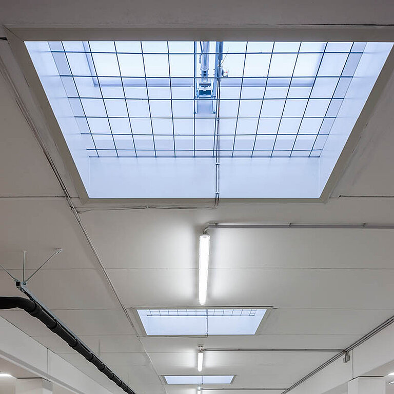 Innenansicht einer Industriehalle mit LAMILUX Flachdach Fenster F100 RWA als zentrales Dachoberlicht zur natürlichen Belichtung und Rauch- und Wärmeabführung