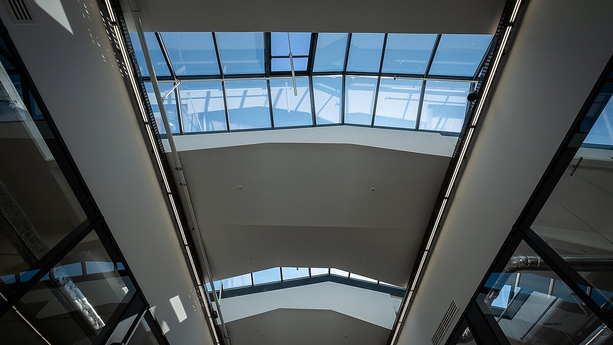 Innenansicht des LAMILUX Glasdach PR60 im Outlet Center Selb mit blauem Himmel und modernem, lichtdurchflutetem Design.