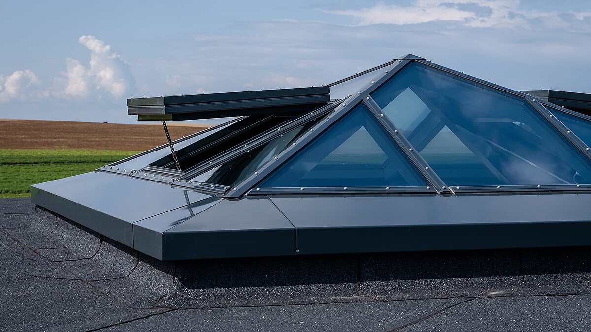Moderne Glaspyramide auf dem Flachdach eines Einfamilienhauses in Wichmannsdorf mit geöffnetem Lüftungsfenster.