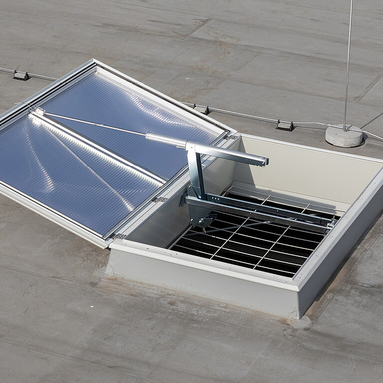 eöffnetes Dachoberlicht auf Flachdach mit transparenter Verglasung und darunterliegendem Gitterrost