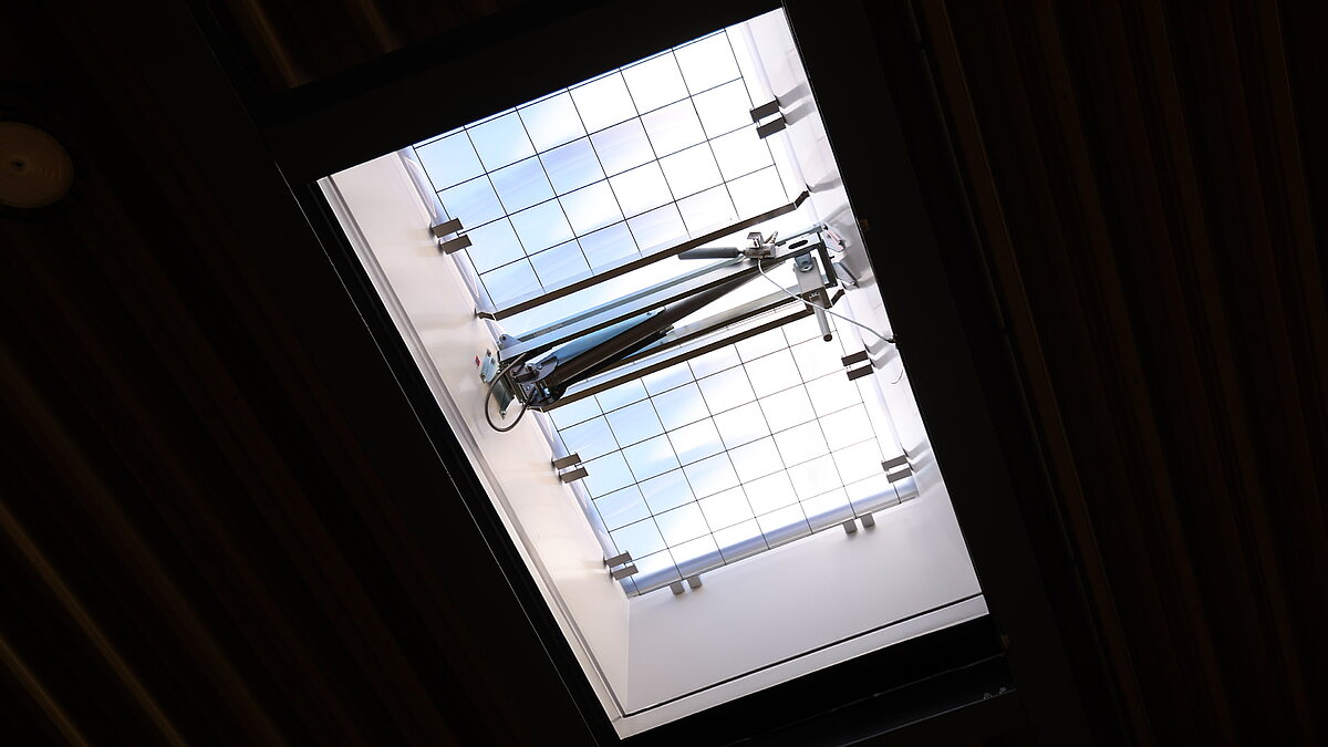 Lichtkuppel F100 W mit integriertem Durchsturzgitter in einer Lagerhalle, Blick von unten auf die Dachöffnung