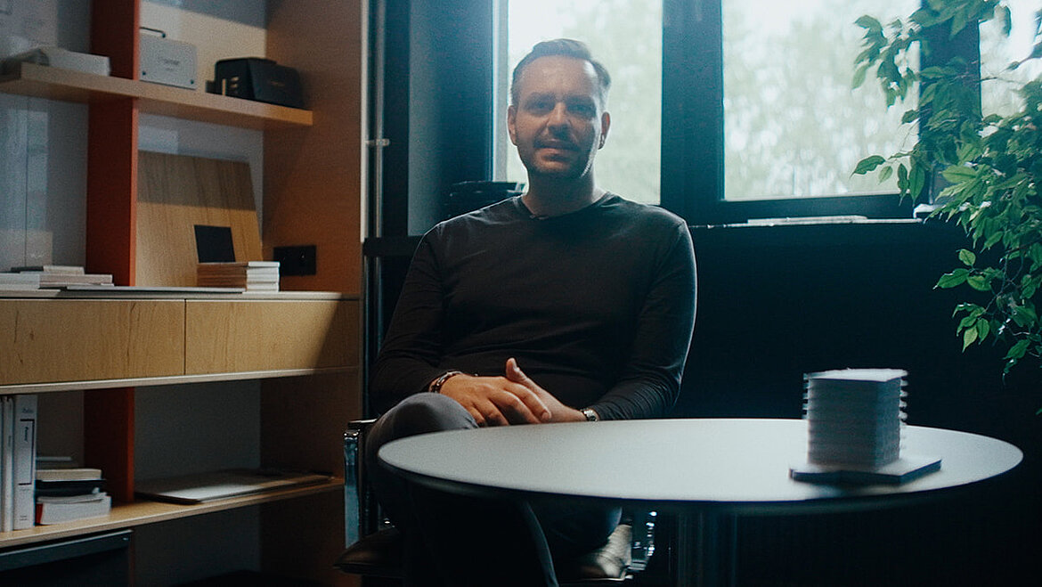 Maciej Franta (Architekt) sitzt an einem Tisch im Büro