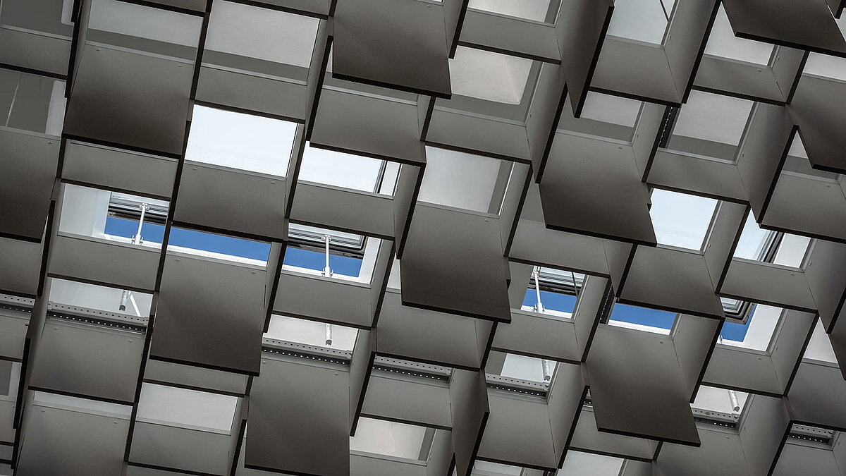 Innenansicht des Landgerichts Weiden mit geometrisch angeordneten Deckenplatten und Oberlichtern, die Tageslicht einlassen.