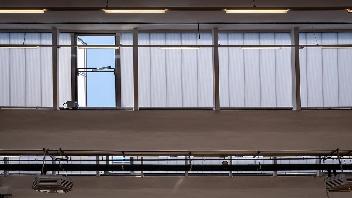 Innenansicht des alten Postbahnhofs Leipzig mit modernisierten Lichtbändern und offenen Fenstern für die Belüftung.