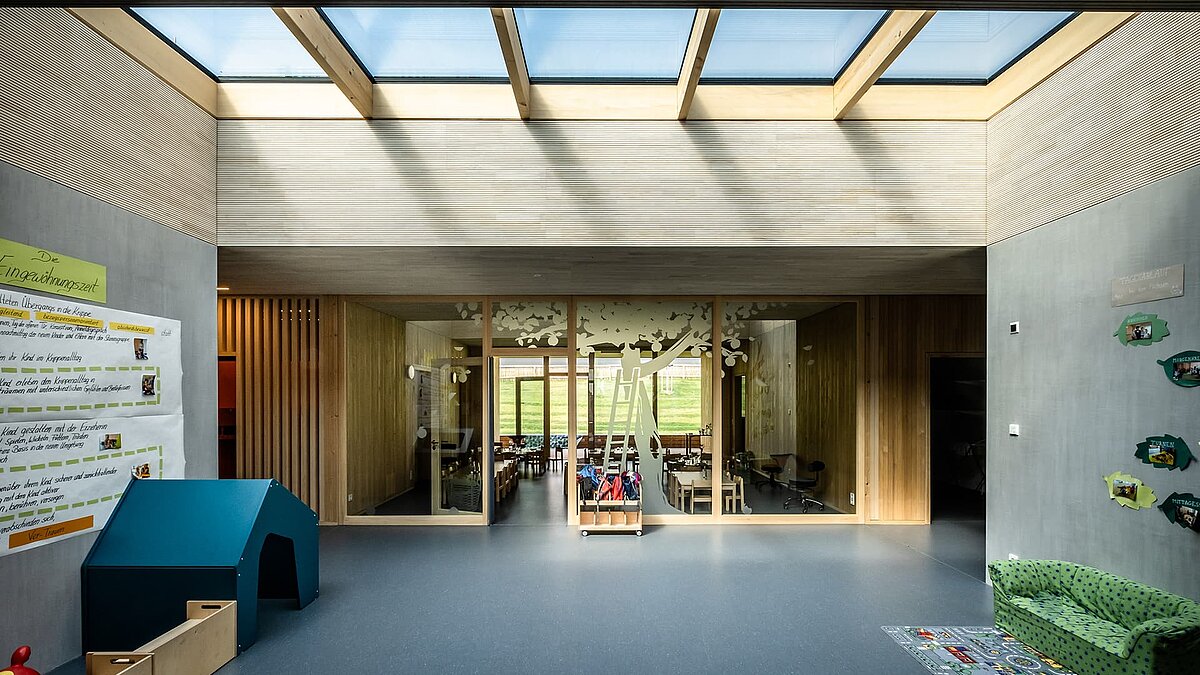 Innenraum der Kinderkrippe Wiggensbach mit großflächigen Glasdächern, die für viel Tageslichteinfall sorgen.
