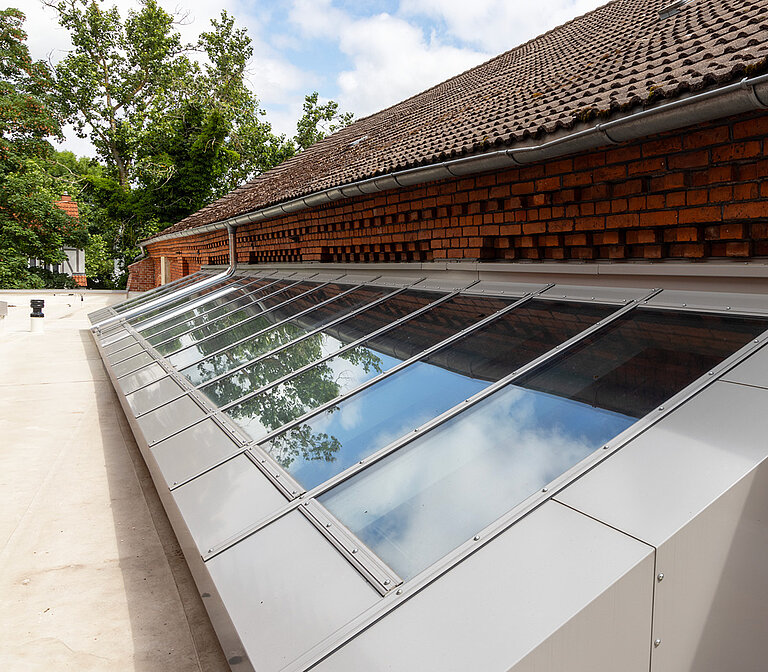 Schräg montierte Oberlichter entlang der Dachkante eines Gebäudes