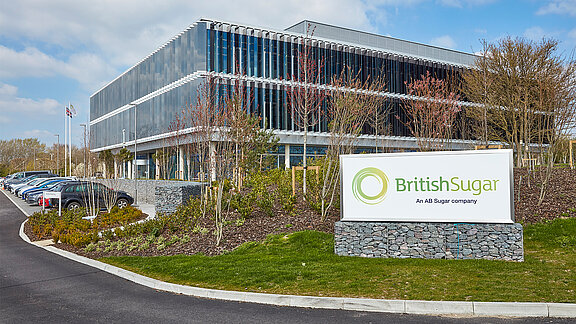 Modernes Bürogebäude von British Sugar mit Glasfassade und Firmenschild im Eingangsbereich