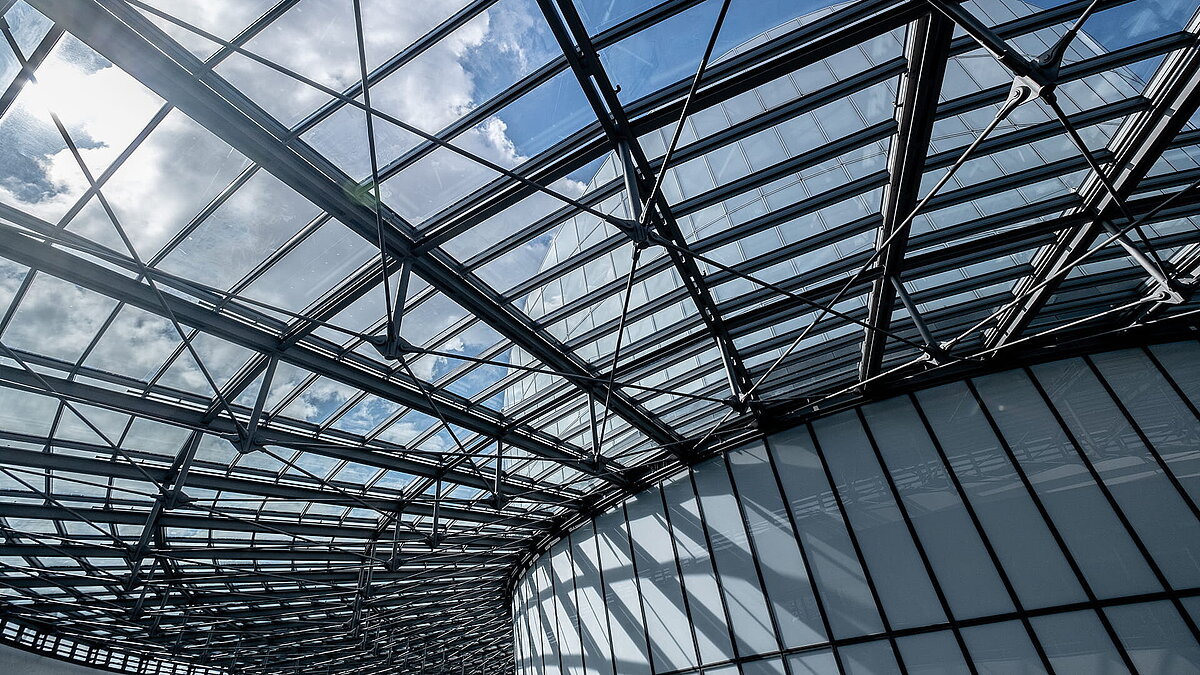 Moderne Glasdachkonstruktion des BMW Group Forschungs- und Innovationszentrums (FIZ) mit Blick auf den Himmel.