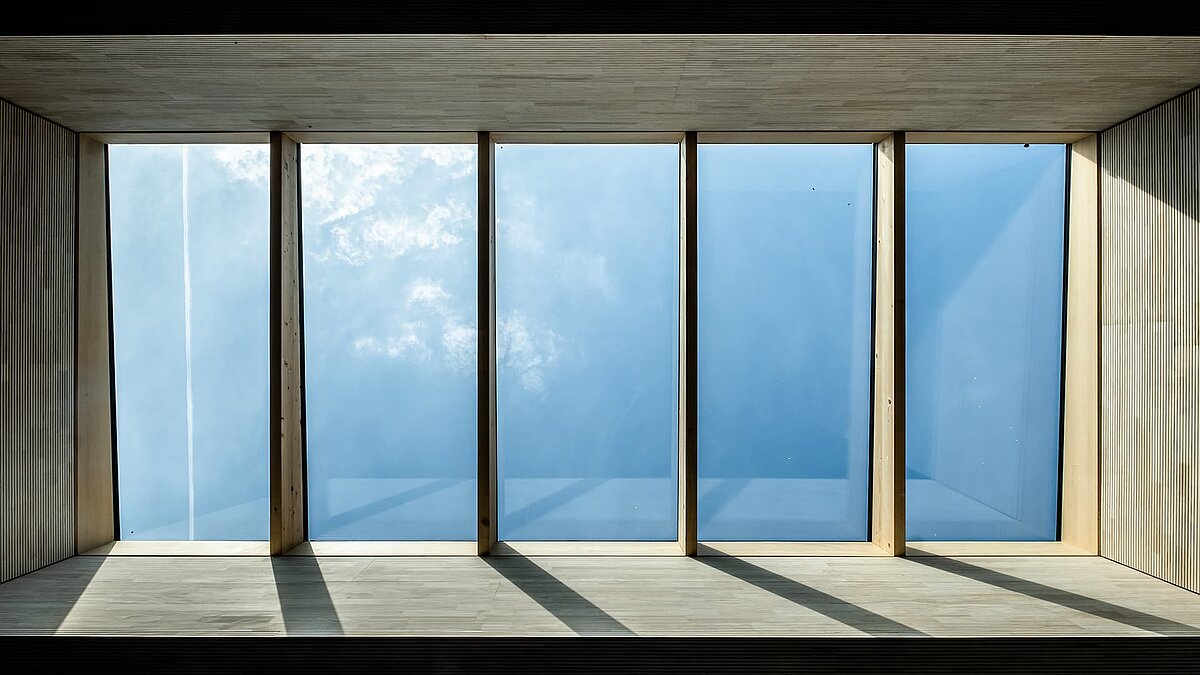 Tageslicht durch große, rechteckige Oberlichter in der Kinderkrippe Wiggensbach, umgeben von Holzverkleidung.