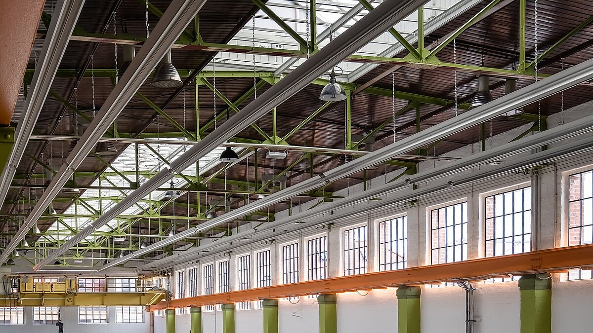 Innenansicht der Eventhalle Zündmagnet in Wurzen mit grünen Stahlträgern, Glasdach, großen Fenstern und industriellem Charme.