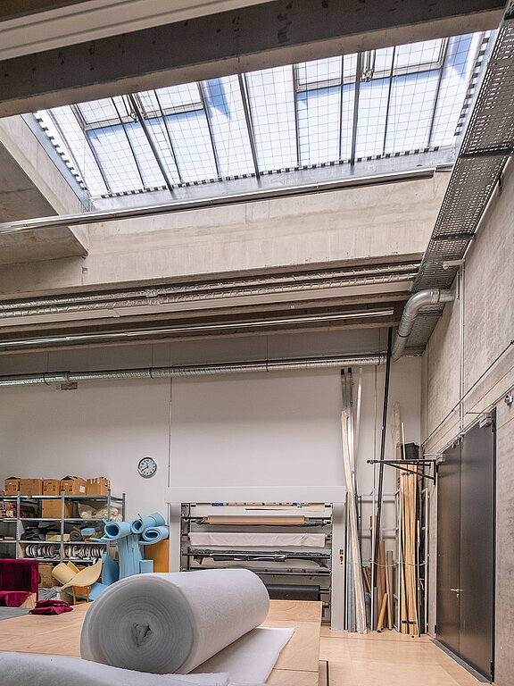 Industriehalle mit Arbeitsmaterialien und großem Oberlicht im Dach