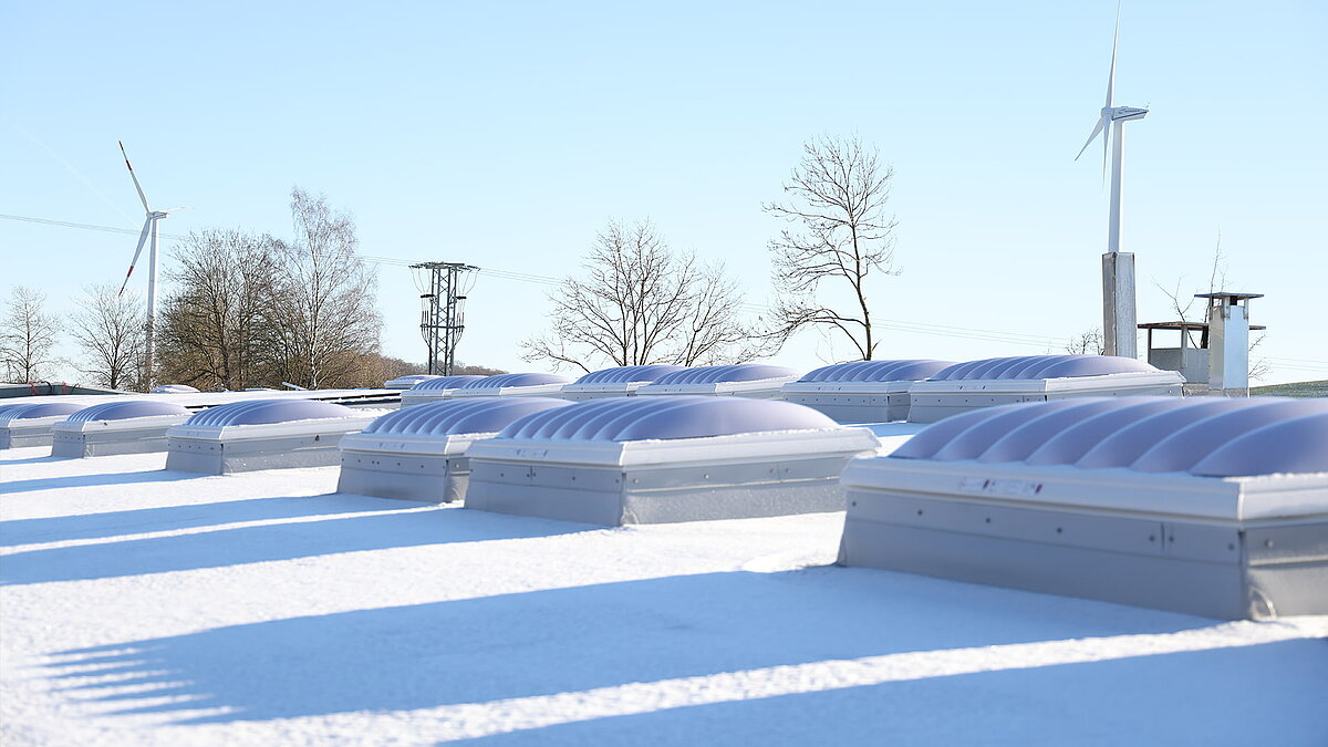 Schneebedecktes Dach des Gebäudes "Ab in die Box" am Diemelsee mit F100W Lichtkuppeln.