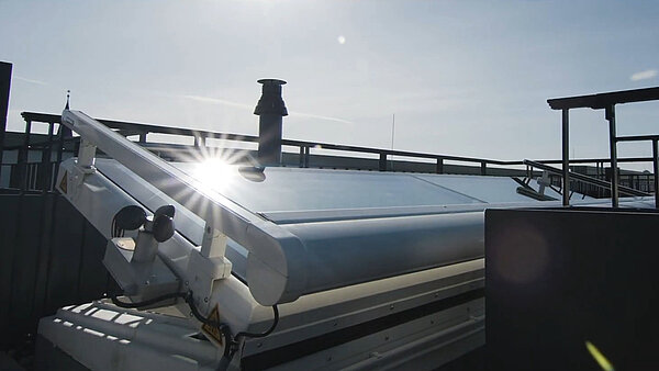 Geöffneter LAMILUX Flachdach Ausstieg mit Sonnenspiegelung auf der Glasfläche.