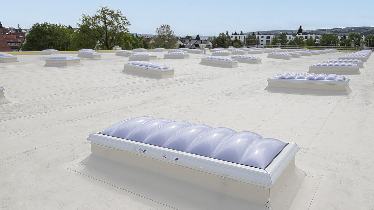 Dach mit innovativen Tageslichtlösungen bei Kärcher mit kuppelförmigen Oberlichtern für verbesserte Sicherheit und Effizienz.