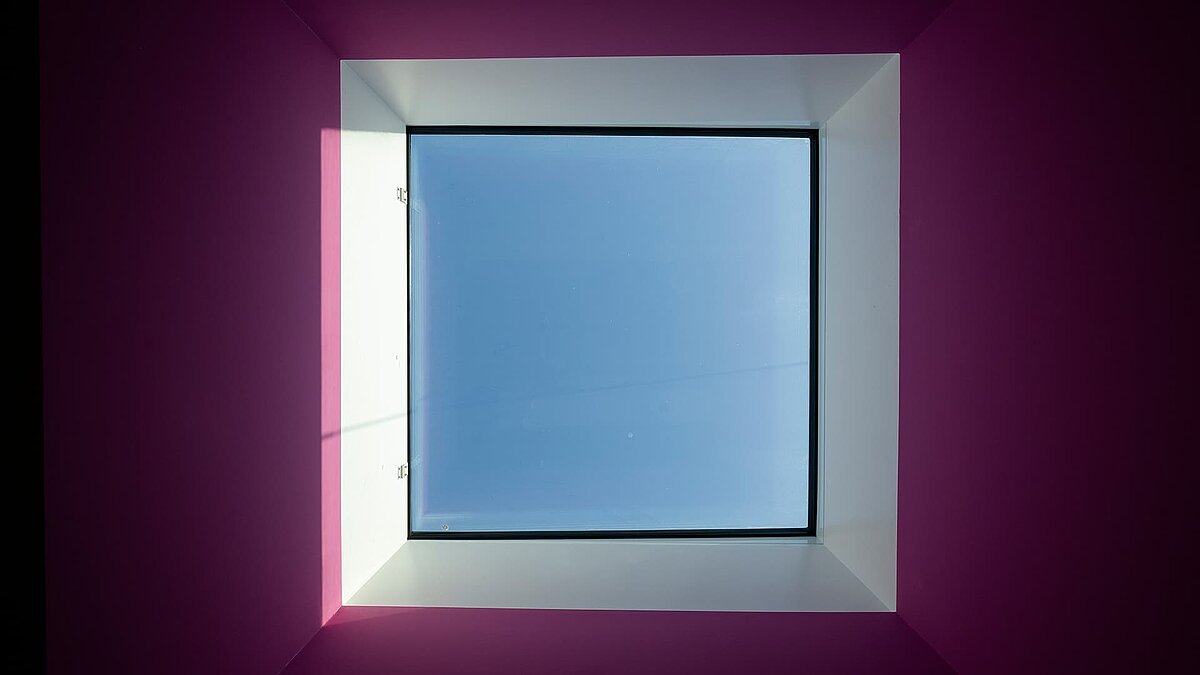 Quadratförmiges Dachfenster im Kindergarten „World of Kids“ mit LAMILUX Tageslichtsystemen, lila Wandgestaltung.