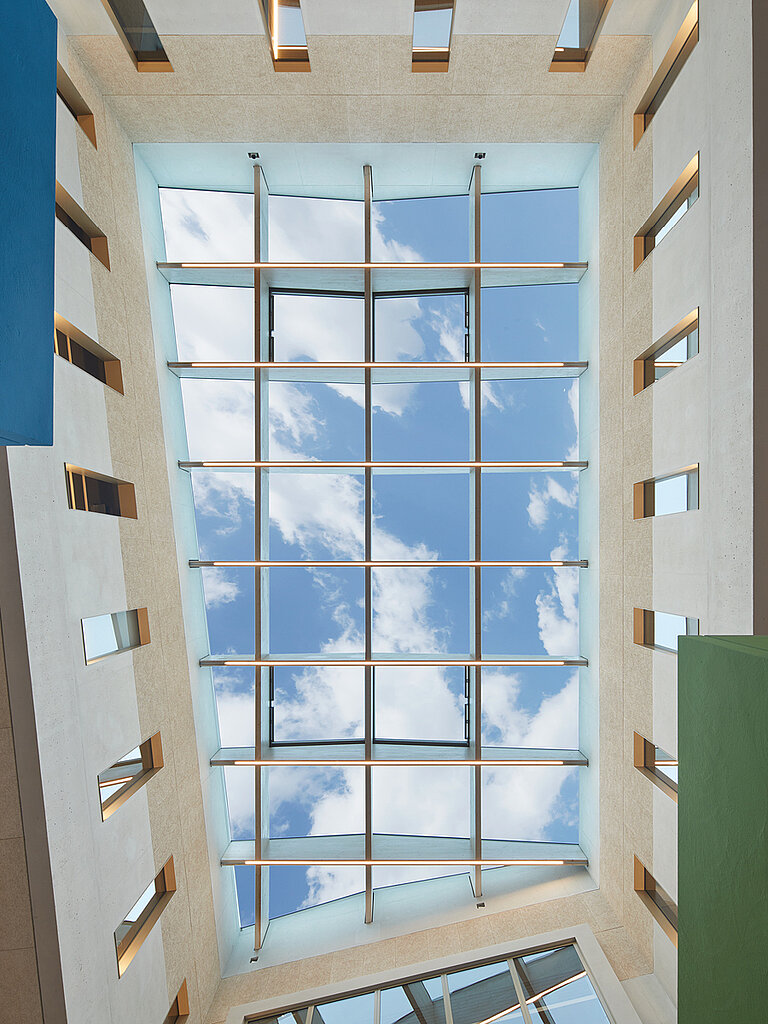 Blick von unten auf ein Flachdach Fenster mit blauem Himmel und ein paar weißen Wolken darüber