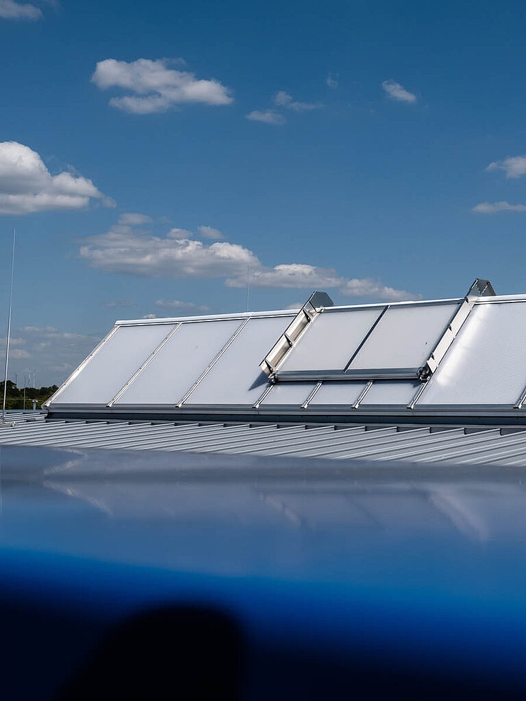 LAMILUX Lichtband Satteldachform auf Flachdach bei klarem Himmel zur natürlichen Tageslichtversorgung